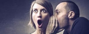 Man telling woman a secret who is shocked