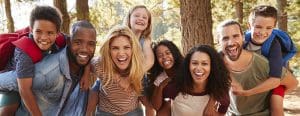 Diverse group of adults and children in the woods smiling