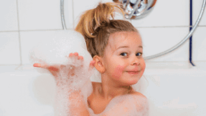 Little girl in the bathtub happy with bubbles