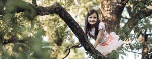 Little girl in pretty dress up in a tree