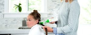 Mom applying lice clinics of america lice remover gel to daughters hair