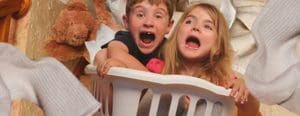 kids in laundry basket screaming with towels and teddy flying through the air