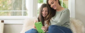 Mom and daughter cuddled up looking at a tablet