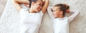 Mom and daughter laying on their backs smiling at each other