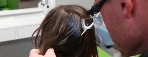 Lice technician looking through magnifying lens looking for head lice during a screening