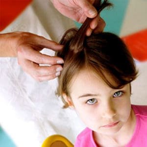 Little girl hoping it's not lice while an adult looks in her hair