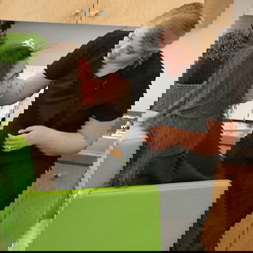 Technician performing heated air head lice treatment and making sure client is doing well