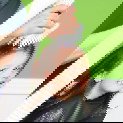 Little girl with brown hair smiling at the camera with the AirAllé device right on the top of her head