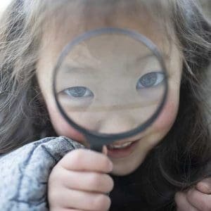 LIttle girl with magnifying glass over her face